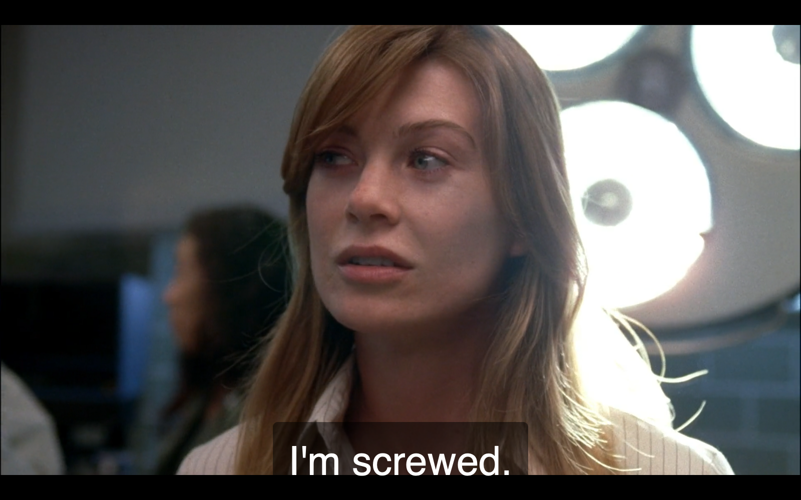 Still of Ellen Pompeo as Meredith Grey, a young brown-haired white woman, in the pilot episode of Grey’s Anatomy, in a brightly lit OR. The show’s subtitle reads, “I’m screwed.”