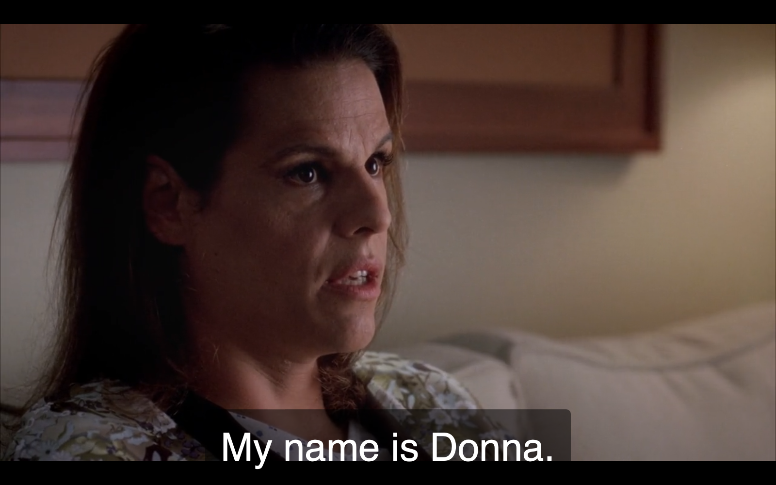 Still from episode 43 of Grey's Anatomy. Donna, a white trans woman patient in a flowery, monochromatic robe, is saying, “My name is Donna.”