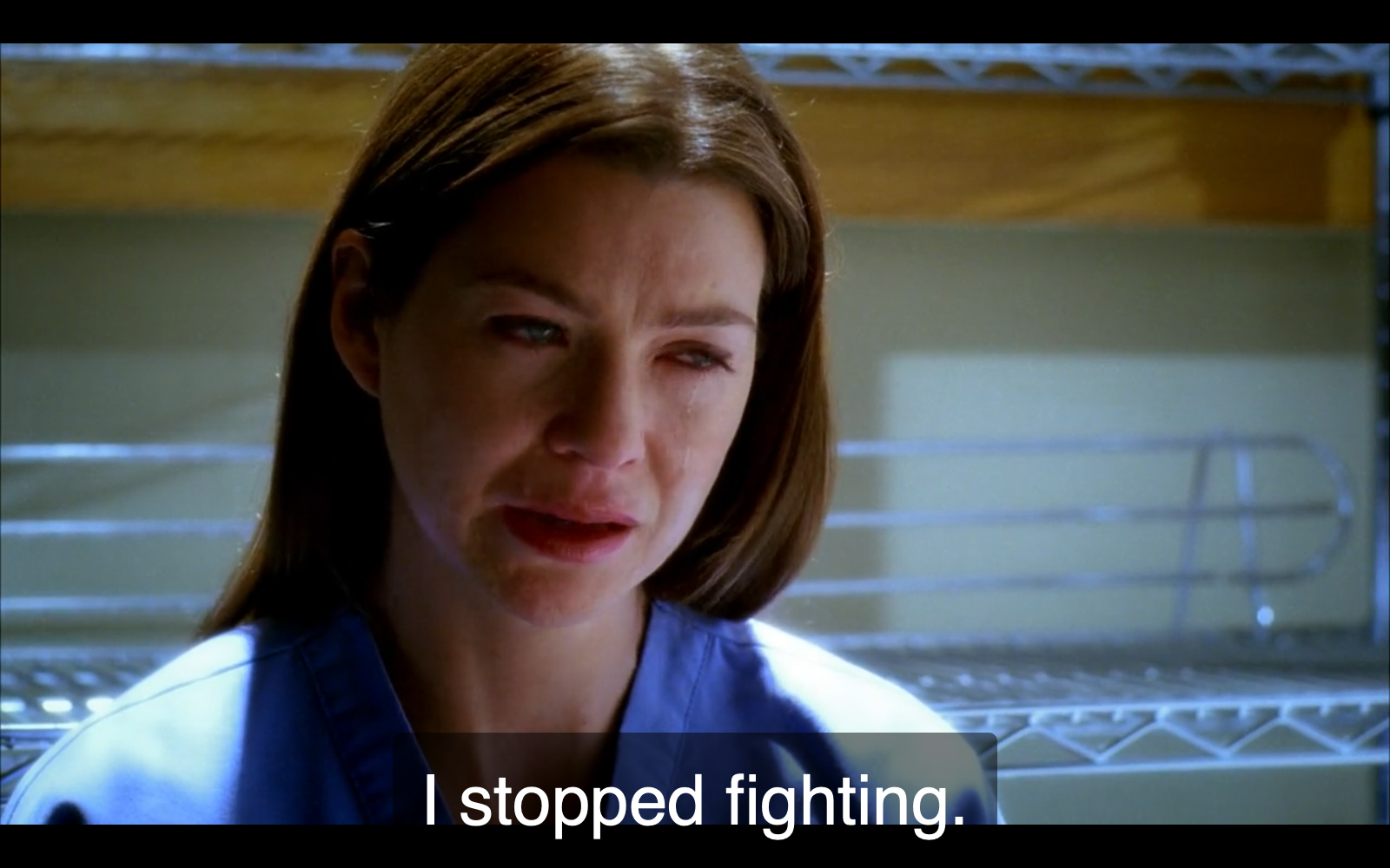 Still from episode 53 of Grey's Anatomy. Meredith Grey, in blue scrubs, is looking down and despondent, crying while saying, “I stopped fighting.”